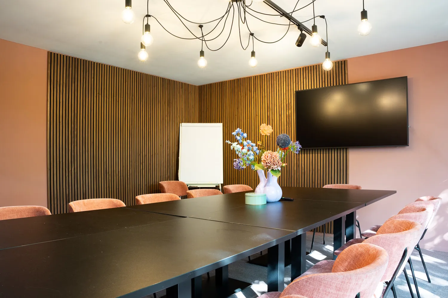 Vergaderruimte bij Just JP met lange tafel en beeldscherm